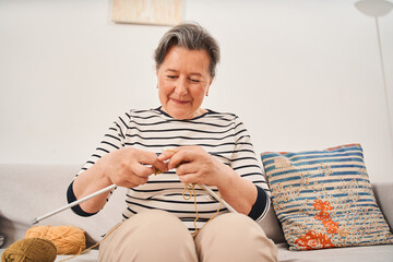 Poster - Woman wearing domestic clothes holding knitting needles while knitting