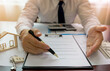 © Pravinrus - Bank officer or house seller agents showing point signature on the house purchase agreement. Real estate concept.