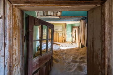 Abandoned building being taken over by encroaching sand in the old mining town of Kolmanskop near Luderitz, Namib Desert, Namibia.