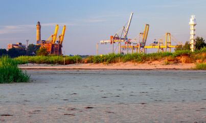 Swinoujscie. Old lighthouse and large cranes in the port.