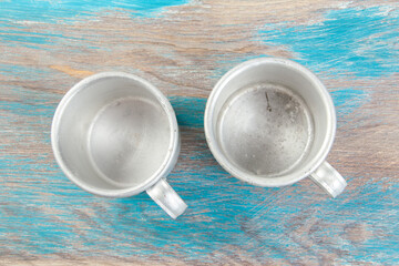 Old metal mugs on wooden background