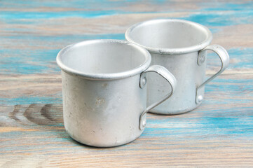 Old metal mugs on wooden background