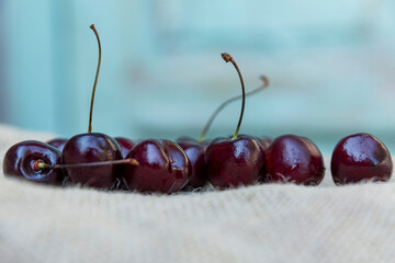 Ripe cherries on burlap on a blue wooden background. Vitamins from nature. Close-up.