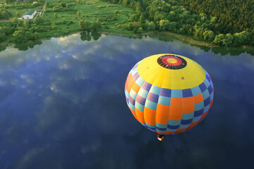 Yellow-blue balloon over the lake on a background of dawn.