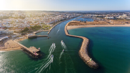 Wall Mural - Aerial view from the sky of the Portuguese coastline of the Algarve zone of Lagos city. Boats and ships are moving in the direction of the port.