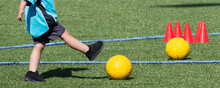 Young Child Kicking A Yellow Soccer Ball