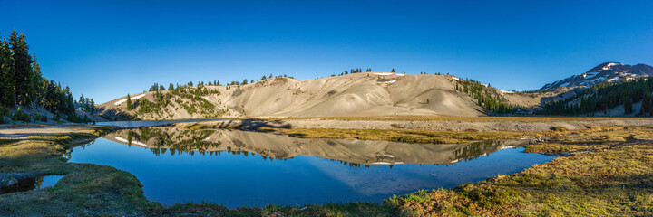 Wall Mural - panoramic view of clear, still alpine lake reflecting surrounding slopes of pumice covered moraine w