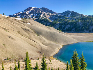 Wall Mural - clear blue alpine lake surrounded by pumice covered moraine and volcanic mountain peaks.