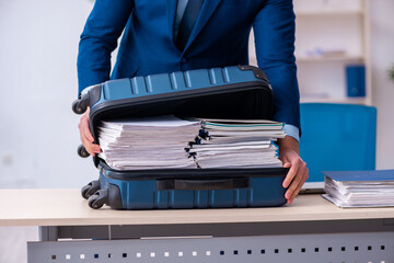 Young male employee preparing for business trip at workplace