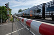 Selective focus view at red and white level crossing railway barrier which block the road and regional train move on the rail on countryside in Germany.	