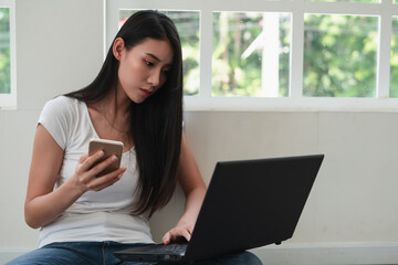 woman wearing white t-shirt using laptop and ceel phone work in living room