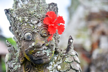 Statue In Taman Ayun Temple With Red Flower On The Ear