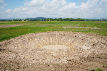 Wall Mural - A large hole in the middle of a field, a pond dug.