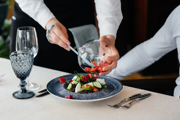 Wall Mural - The waiter makes an exquisite serving of seafood salad, tuna and black caviar in a beautiful serving on the table in the restaurant. Exquisite delicacies of haute cuisine close-up.