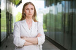 © Екатерина Переславце - Business woman portrait Crossed arms. Happy successful professional portrait near an office building. Young caucasian business woman with clasped hands standing outside. Female business leader concept