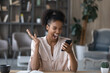 © fizkes - Overjoyed African American woman rejoicing success, holding smartphone, reading news good news in message, excited businesswoman received job promotion, money refund or reward, online lottery win