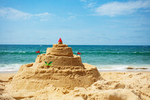 Sandcastle On The Beach With Toys And Palm Tree