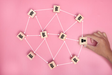 hand holding wood blocks connected together on pink background. teamwork, network concept.
