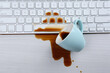 Cup of coffee spilled over computer keyboard on white wooden table, flat lay