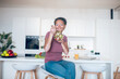 © zinkevych - A dark-skinned woman sitting in the kitchen and eating salad