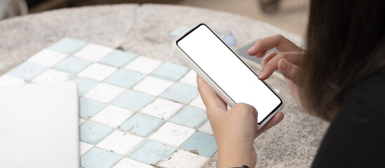 Woman's hands holding or using smartphone with two hands. Smartphone with white blank on screen, Cellphone mockup.