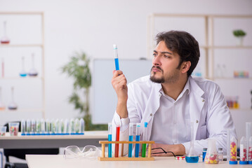 Young male chemist in drugs synthesis concept