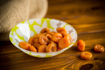 Wall Mural - delicious dried apricots in a bowl on a wooden table