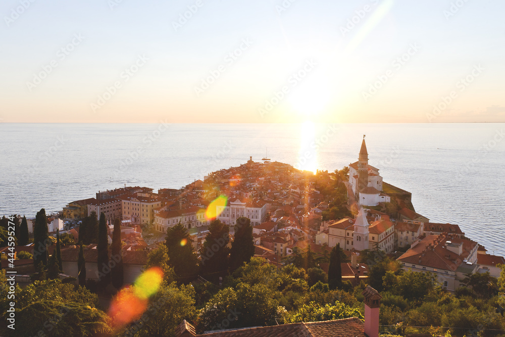Scenic view of red roofs of the historical center of old town Piran with main church against the sunset sky and blue Adriatic sea. Aerial view, coast of Slovenia.  - obrazy, fototapety, plakaty 