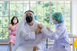 © godji10 - Asian doctor use syringe to injecting covid-19 vaccine into the Arab people in the hospital to prevent outbreak of coronavirus. Immunization, Covid-19 vaccination clinic, Coronavirus global pandemic.