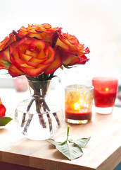 Wall Mural - Red-yellow roses in vase. Autumn still life with flowers and candles on table 