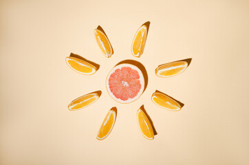 Orange slices arranged around a red grapefruit on a light orange background.