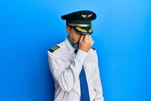 Middle Age Man With Beard And Grey Hair Wearing Airplane Pilot Uniform Tired Rubbing Nose And Eyes Feeling Fatigue And Headache. Stress And Frustration Concept.