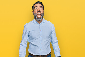 Wall Mural - Middle aged man with beard wearing business shirt angry and mad screaming frustrated and furious, shouting with anger. rage and aggressive concept.