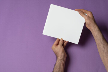 Poster - Male hands holding a catalog with blank cover on purple background - editable mockup template