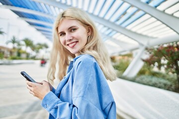 Young blonde woman outdoors on a sunny day using smartphone