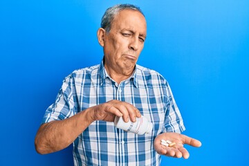 Sticker - Senior hispanic man holding pills depressed and worry for distress, crying angry and afraid. sad expression.