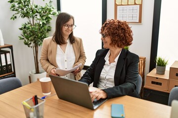 Canvas Print - Group of two women working at the office. Mature woman and down syndrome girl working at inclusive teamwork.