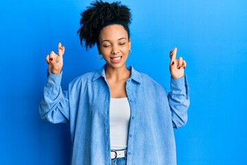 Sticker - Young african american girl wearing casual clothes gesturing finger crossed smiling with hope and eyes closed. luck and superstitious concept.