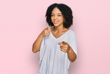 Wall Mural - Young african american girl wearing casual clothes pointing fingers to camera with happy and funny face. good energy and vibes.