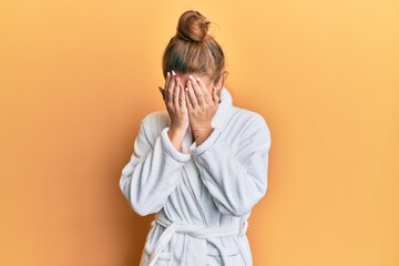 Wall Mural - Young blonde woman wearing bathrobe with sad expression covering face with hands while crying. depression concept.