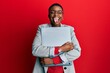 © Krakenimages.com - Young african american businesswoman holding laptop sticking tongue out happy with funny expression.