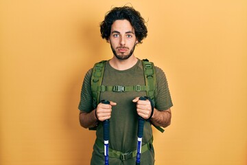 Sticker - Handsome hispanic man wearing backpack holding trekking poles depressed and worry for distress, crying angry and afraid. sad expression.