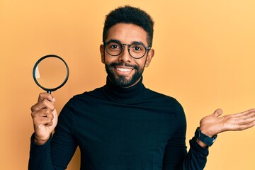 Wall Mural - Handsome hispanic man with beard holding magnifying glass celebrating achievement with happy smile and winner expression with raised hand