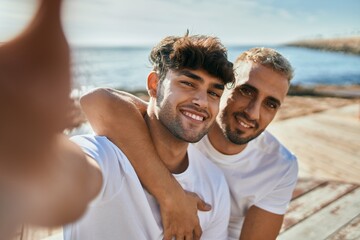 Sticker - Young gay couple smiling happy making selfie by the smartphone at the beach.