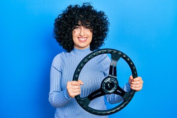 Sticker - Young middle east woman holding steering wheel smiling with a happy and cool smile on face. showing teeth.