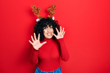 Sticker - Young middle east woman wearing cute christmas reindeer horns afraid and terrified with fear expression stop gesture with hands, shouting in shock. panic concept.