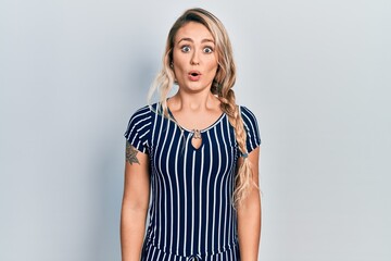 Wall Mural - Beautiful young blonde woman wearing casual striped dress afraid and shocked with surprise expression, fear and excited face.