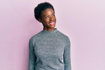 Canvas Print - Young african american girl wearing casual clothes looking away to side with smile on face, natural expression. laughing confident.