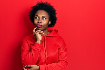 Young african american woman wearing casual sweatshirt with hand on chin thinking about question, pensive expression. smiling with thoughtful face. doubt concept.