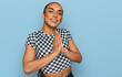 © Krakenimages.com - Hispanic transgender man wearing make up and long hair wearing modern clothes praying with hands together asking for forgiveness smiling confident.